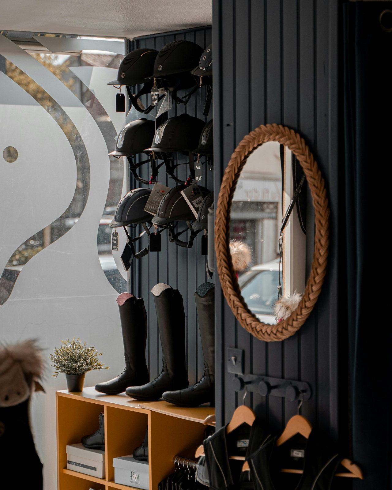La boutique de Langon : casques, bottes et miroir tressé sur boiseries marine